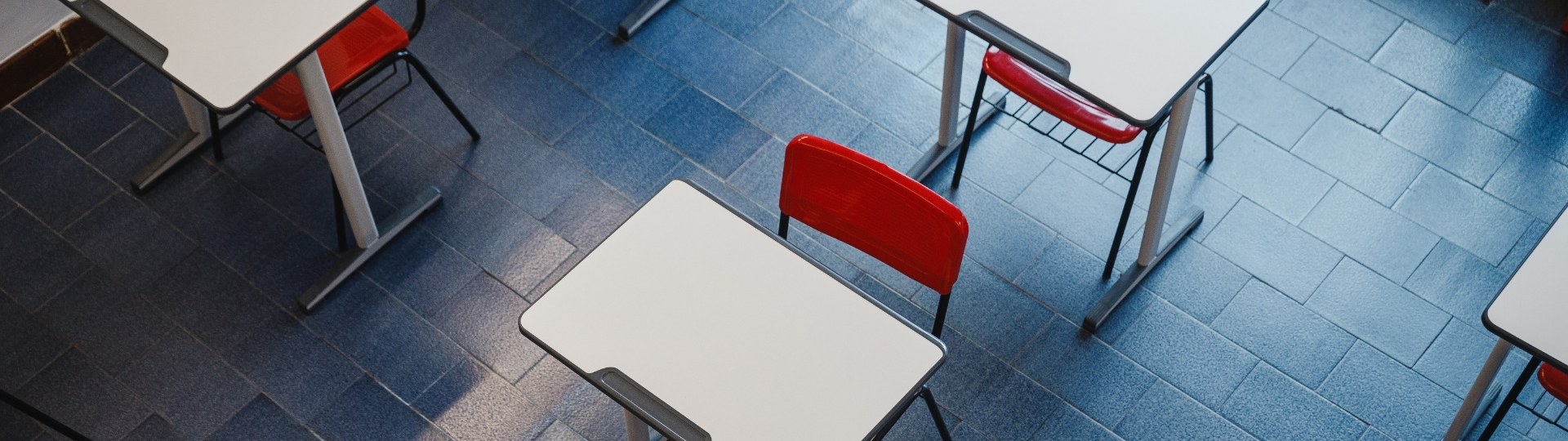 Aula de The Real Academy Of English de clases de inglés con pupitres blancos y sillas rojas vista desde arriba
